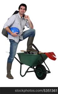 Tradesman with his foot propped up on a wheelbarrow