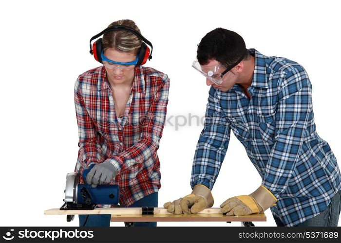 Tradespeople cutting a wooden plank with a circular saw