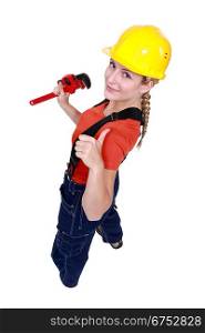 Tradeswoman giving the thumb&acute;s up and holding a pipe wrench