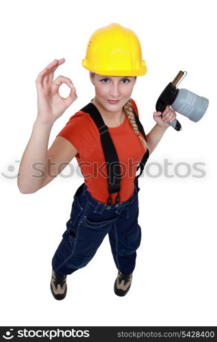 Tradeswoman holding a blowtorch and giving the a-ok sign