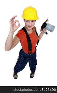Tradeswoman holding a blowtorch and giving the a-ok sign