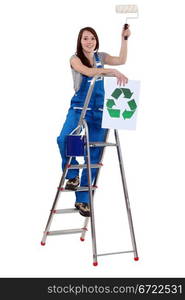 Tradeswoman holding a paint roller and a poster