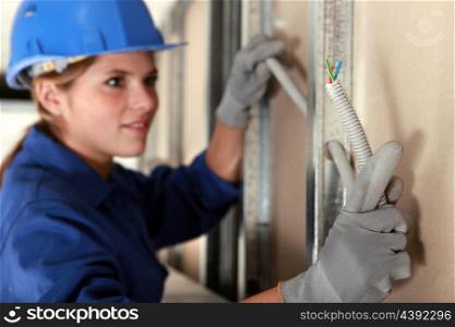 Tradeswoman installing electrical wiring
