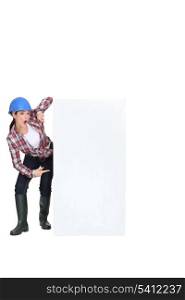 Tradeswoman pointing to a blank sign