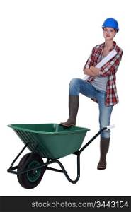 Tradeswoman with her foot propped on a wheelbarrow