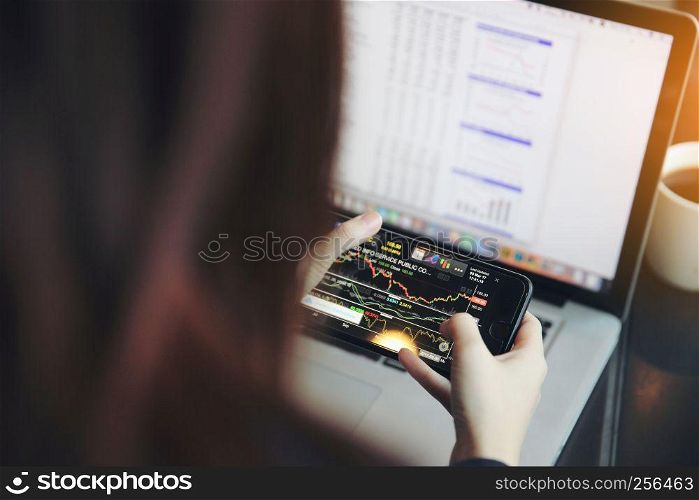 trading online on smartphone and notebook with business woman hand