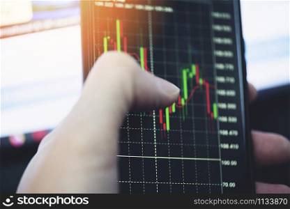 Trading stock graph or forex online with application on smartphone / Businessman trading stocks chart with statistic analysis price table market financial on mobile phone finance data and technology