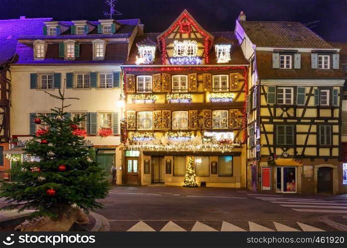 Traditional Alsatian half-timbered houses in old town of Colmar, decorated and illuminated at snowy christmas night, Alsace, France. Christmas street at night in Colmar, Alsace, France