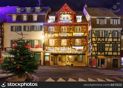 Traditional Alsatian half-timbered houses in old town of Colmar, decorated and illuminated at snowy christmas night, Alsace, France. Christmas street at night in Colmar, Alsace, France