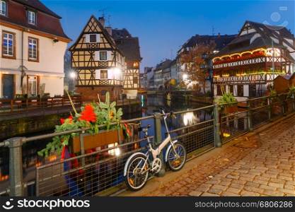 Traditional Alsatian half-timbered houses with mirror reflections in Petite France during twilight blue hour decorated and illuminated at christmas time, Strasbourg, Alsace, France