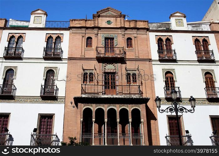 Traditional Andalusian apartment houses with arched windows in El Arenal historic quarter of Seville, Spain.