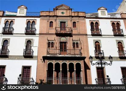 Traditional Andalusian apartment houses with arched windows in El Arenal historic quarter of Seville, Spain.