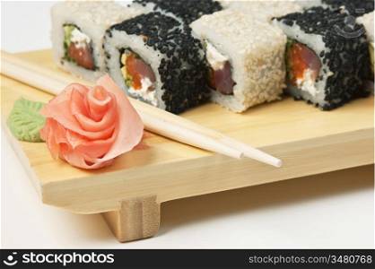 Traditional Asian food sushi on wooden plate isolated on white background