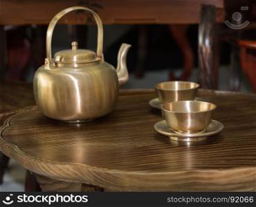 Traditional Asian Golden Teapot and Cups on Little Wooden Table