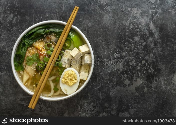 Traditional asian noodle soup Udon with tofu, bok choy cabbage, and kimchi. Vegetarian recipe.