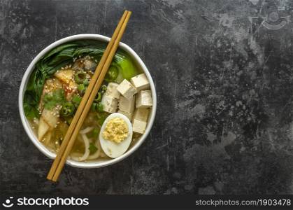 Traditional asian noodle soup Udon with tofu, bok choy cabbage, and kimchi. Vegetarian recipe.