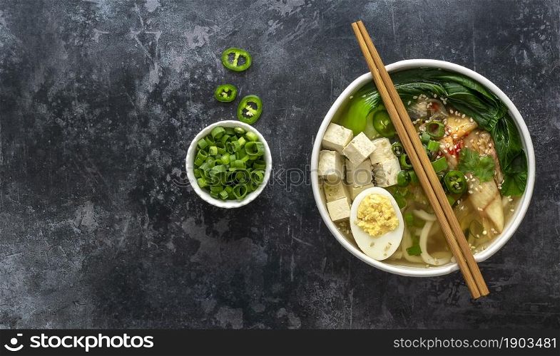 Traditional asian noodle soup Udon with tofu, bok choy cabbage, and kimchi. Vegetarian recipe. Copy space.