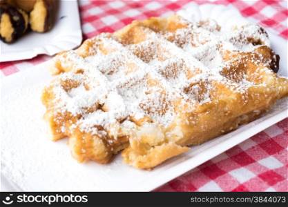 Traditional Belgian Plain Waffle Dusted with Icing Sugar on Red Checked Tablecloth