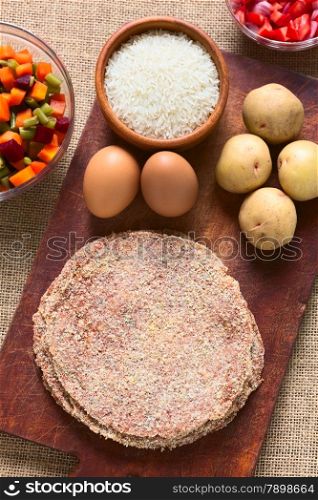 Traditional Bolivian meat called Silpancho, which is a breaded flat, round piece of beef meat, served with fried egg, rice, fried potatoes and vegetables (carrot, bean, beetroot), photographed with natural light