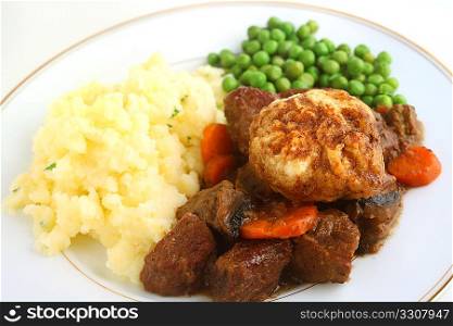 Traditional British beef stew topped with dumplings and served with parsley mashed potatoes and peas.