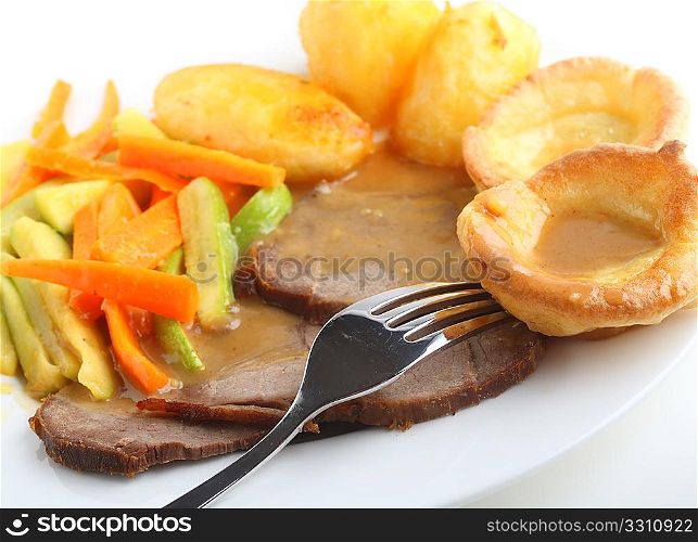 Traditional british meal of roast beef and yorkshire pudding (popovers) served with roasted potatoes and julienned sauteed carrots and courgettes, with plenty of gravy.