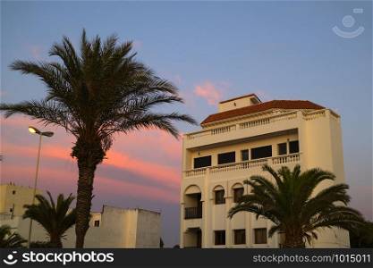Traditional built apartments with palm trees at the boulevard of Assilah at twilight
