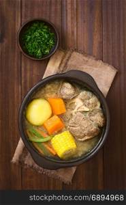 Traditional Chilean Cazuela de Vacuno or Cazuela de Carne, a beef soup with potato, corn, pumpkin, carrot, bell pepper, onion and rice, cut parsley on the side, photographed overhead on dark wood with natural light (Selective Focus, Focus on the soup). Chilean Cazuela de Vacuno or Carne, Beef Soup