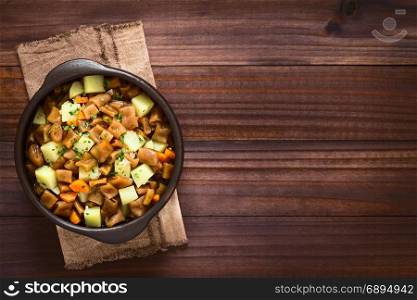 Traditional Chilean Estofado or Guiso de Cochayuyo (lat. Durvillaea antarctica), a vegan stew of bull kelp, potato, carrot and onion, served with parsley in rustic bowl, photographed overhead on dark wood with natural light. Chilean Estofado or Guiso de Cochayuyo, Bull Kelp Stew