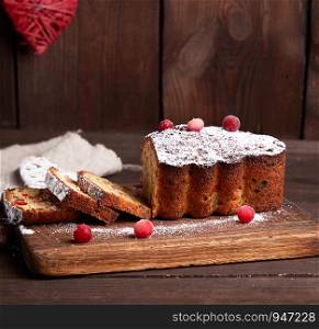 traditional Christmas cake stollen cut into pieces on a brown wooden board