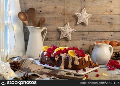Traditional christmas cinnamon cake decorated with fruits and spekulatius cookies cream on a kitchen countertop.