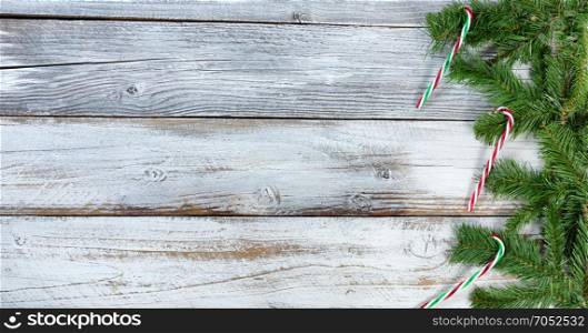 Traditional Christmas evergreen branches with candy cane ornament decorations on rustic knotty wood in flat lay format