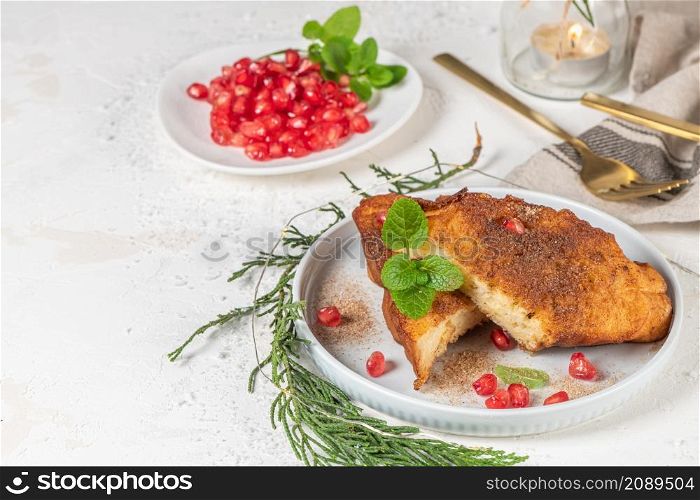 Traditional Christmas Rabanadas with lemon zest, pomegranate, pine nuts and cinnamon. Spanish Torrijas or french toasts close up on the countertop