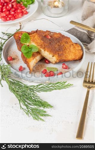 Traditional Christmas Rabanadas with lemon zest, pomegranate, pine nuts and cinnamon. Spanish Torrijas or french toasts close up on the countertop