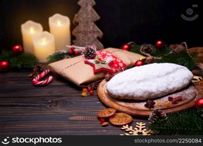 Traditional Christmas stollen cake and New Year decorations on wooden background. High quality photo. Traditional Christmas stollen cake and New Year decorations on wooden background