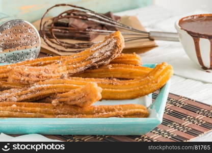 Traditional churros with hot chocolate dipping sauce on wooden counter top.