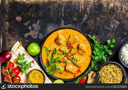 Traditional curry and ingredients on dark background. Curry, lime, ginger, chili, naan bread, rice, couscous, herbs and spices Flat lay. Traditional curry and ingredients. Traditional curry and ingredients