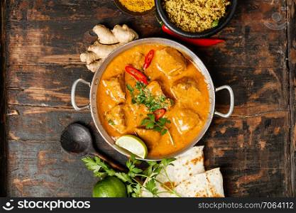 Traditional curry and ingredients on dark background. Curry, lime, ginger, chili, naan bread, rice, couscous, herbs and spices Flat lay. Traditional curry and ingredients