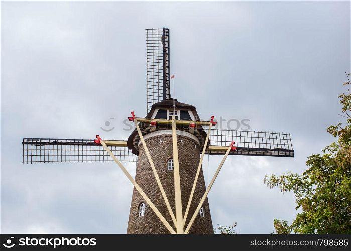 Traditional dutch windmill in the Netherlands close-up with green trees. Traditional dutch windmill in the Netherlands close-up