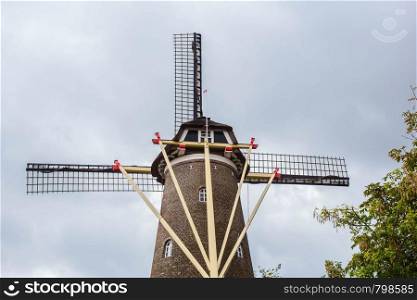 Traditional dutch windmill in the Netherlands close-up with green trees. Traditional dutch windmill in the Netherlands close-up