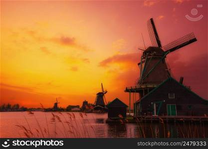 Traditional Dutch windmills on the canal bank at warm sunset light in Netherlands near Amsterdam