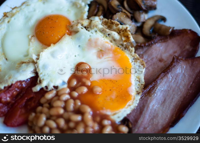 Traditional English breakfast - fried bacon, mushrooms, eggs, baked beens and tomatos