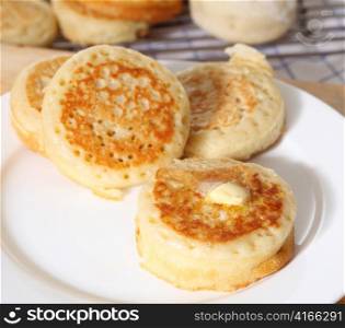 Traditional English homemade crumpets with a knob of butter on the front one.