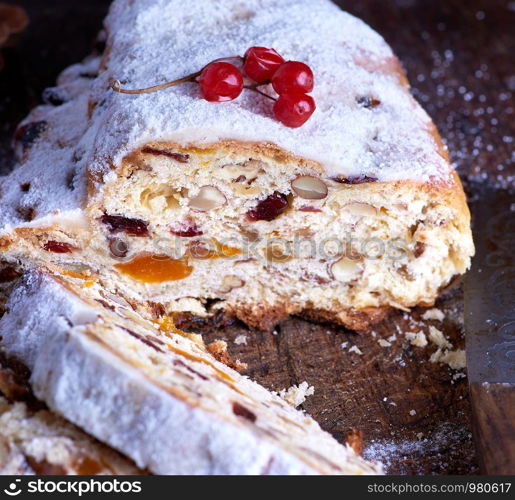 Traditional European Christmas pastry, home baked stollen with spices and dried fruit. Sliced on rustic brown wooden table