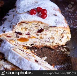 Traditional European Christmas pastry, home baked stollen with spices and dried fruit. Sliced on rustic brown wooden table