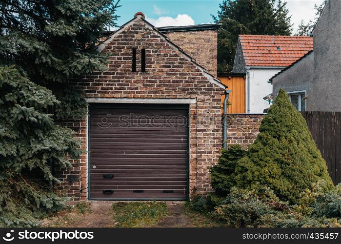 Traditional european garage with red brick and brown gate
