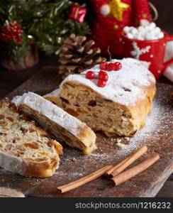 traditional European Stollen cake with nuts and candied fruit on a wooden board, close up