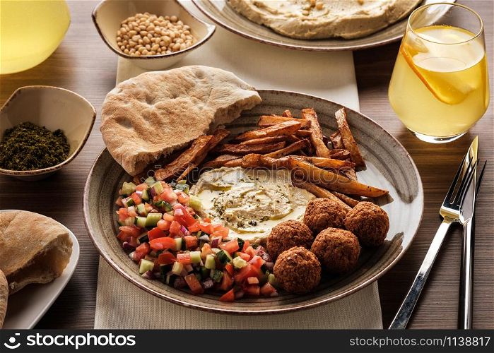 Traditional falafel balls with salad and hummus on a plate.