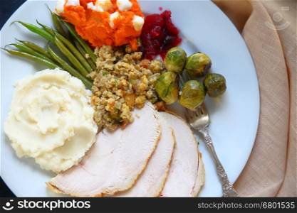 Traditional food served at Thanksgiving including turkey, mashed potatoes, stuffing, green beans, brussels sprouts and mashed sweet potatoes with marshmallows