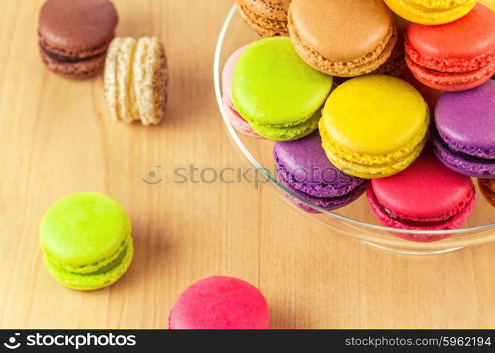 traditional french colorful macarons in a glass cake stand on wooden table