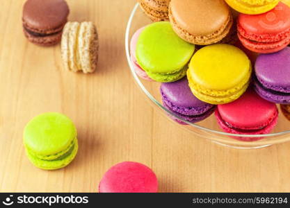 traditional french colorful macarons in a glass cake stand on wooden table